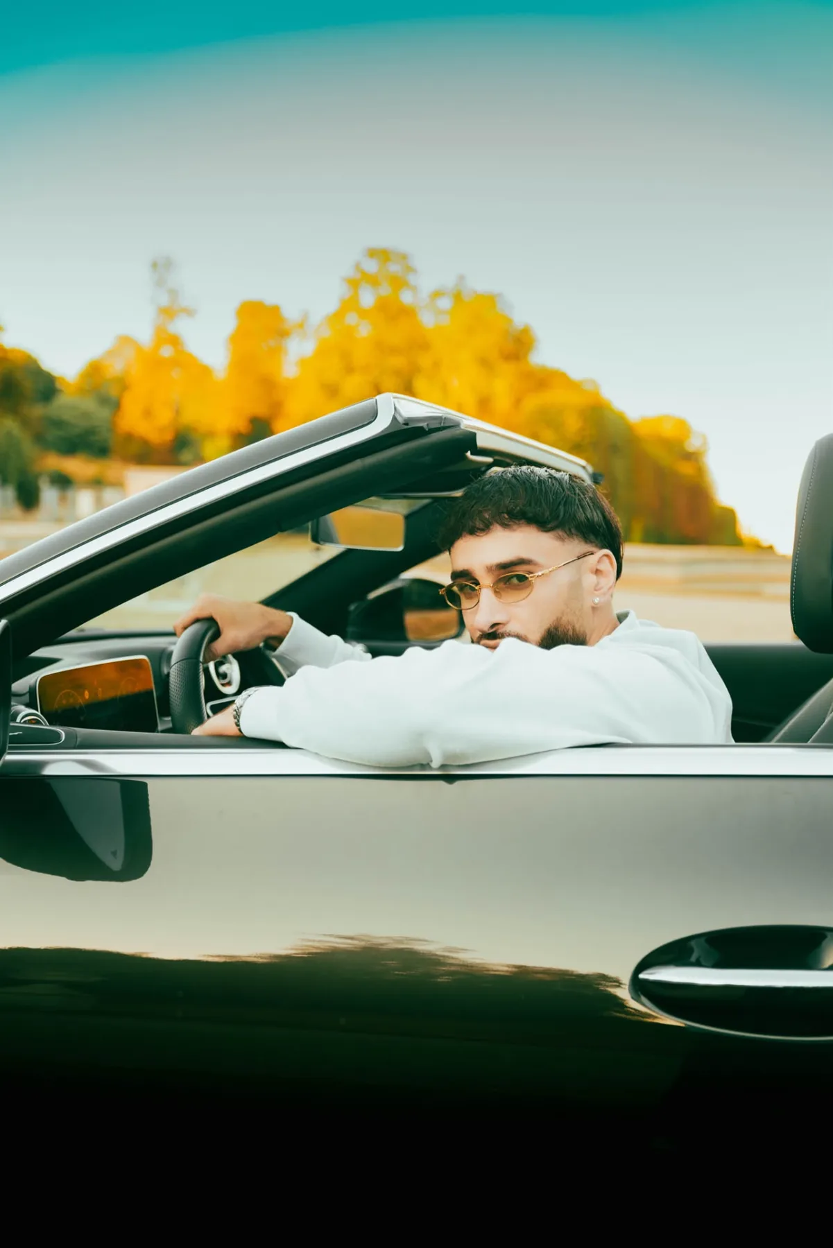 Portrait d'un homme au volant d'un cabriolet au coucher du soleil